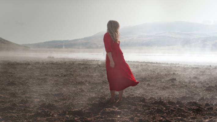 woman in red dress standing on brown soil during daytime