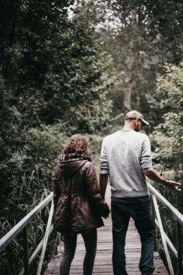 man and woman holding hands walking on bridge during daytime