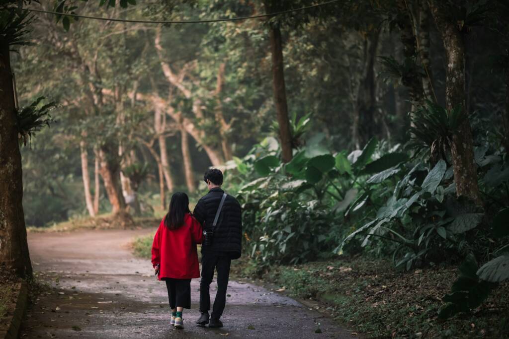 a man and a woman walking down a path in the woods