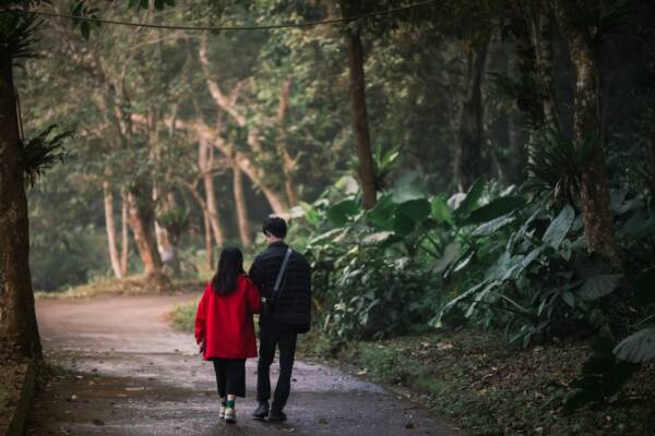 a man and a woman walking down a path in the woods