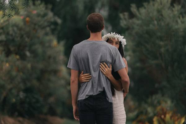 man and woman hugging each other near plants
