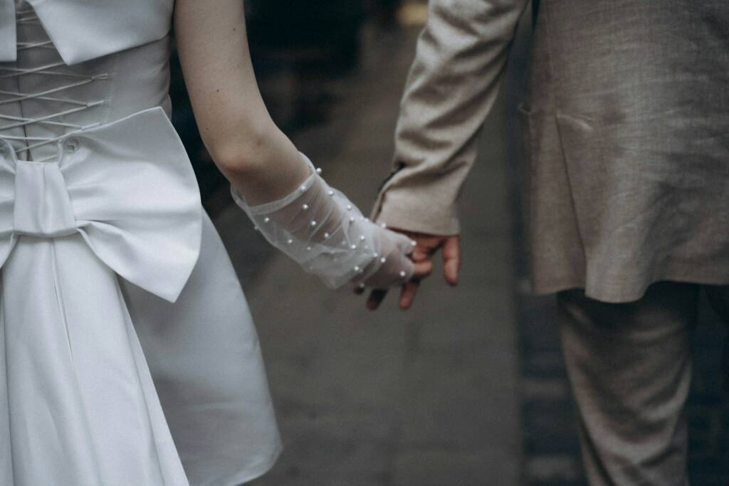 A bride and groom holding hands walking down the street