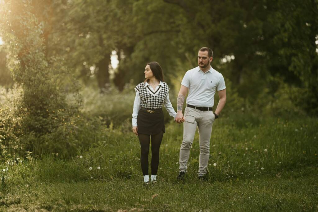 a man and a woman holding hands walking through a field