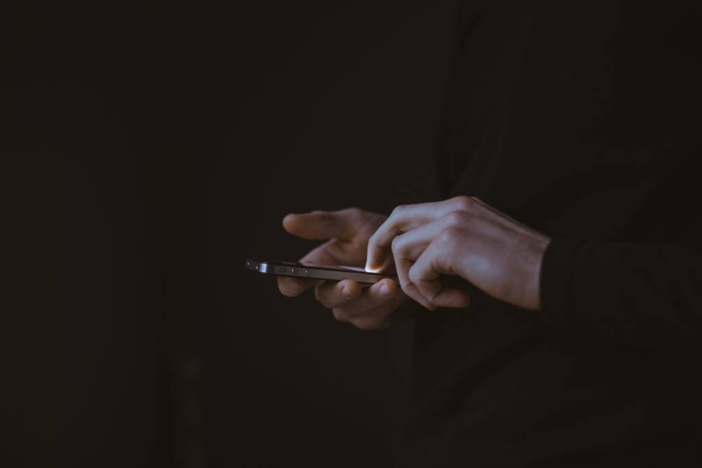 silhouette photo of person holding smartphone