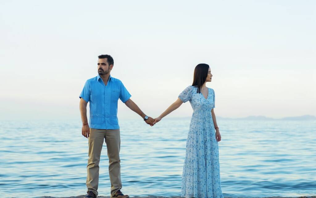 man and woman holding hands while walking on beach during daytime