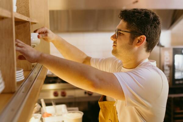 A man in a white shirt is putting something on a shelf