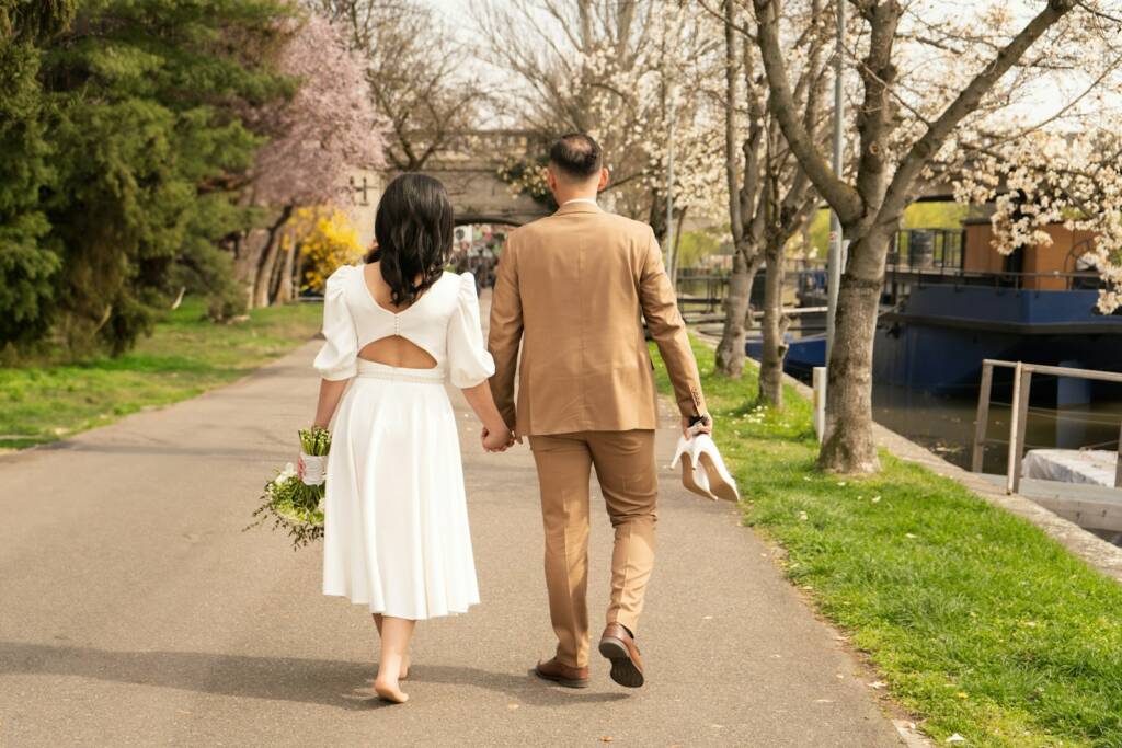 a man and woman walking down a path holding hands