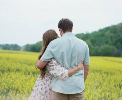 A couple embraces and looks at a field.